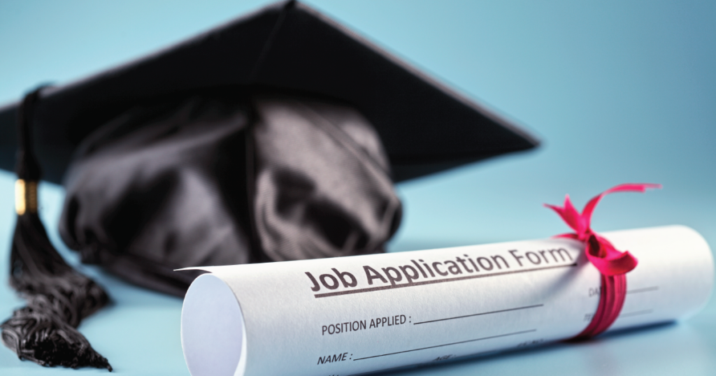 A photo of a rolled-up job application form positioned in front of a graduation black